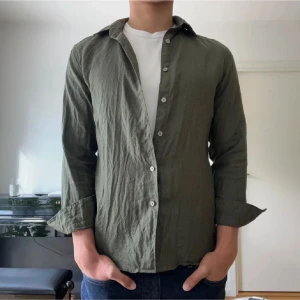 Grön linneskjorta  - Säljer en olivgrön skjorta från Uniqlo i storlek S. Modellen är 184 cm. Nypris 599.
