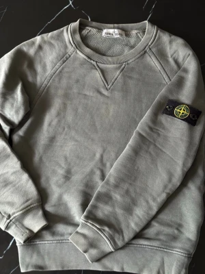 Stone Island Junior sweatshirt 140 cm – Äkta – Fint skick - Säljer en äkta Stone Island Junior sweatshirt i storlek 140 (ca 10 år). Riktigt fin och stilren modell med klassiska avtagbara Stone Island-badgen på armen. Perfekt vardagströja som håller hög kvalitet. ✔ Fint skick ✔ Inga hål  ✔ 100% bomull ✔ Snygg neutral färg som passar till allt Mått: • Längd: 55 cm • Bredd (armhåla till armhåla): 41 cm Passar ca 134–146 cm beroende på passform. Hör av er vid frågor och pris kan alltid diskuteras 🙌