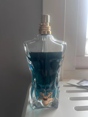 Jean Paul Gaultier Le Beau EdT 125ml - Jean Paul Gaultier Le Beau Eau de Toilette i en unik flaska formad som en manlig torso. Flaskan är genomskinlig med blågrön vätska och har en guldfärgad detalj framtill. Volymen är 125 ml och designen är riktigt ikonisk och stilren.