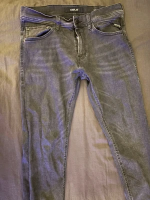 Svarta slim Replay jeans med smal passform - Snygga svarta slim jeans från Replay med smal passform och klassisk femficksdesign. Jeansen har diskreta slitningar och tydliga sömmar på bakfickorna. Tillverkade i stretchigt denim för extra komfort. Är alltid öppen för att diskutera pris