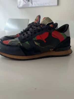 Valentino rockrunners  - Tjena! Säljer dessa snygga Valentino Rockrunners i storlek 42 för 1100 kr. Modellen har det klassiska camouflagemönstret i rött och grönt. Skorna är använda och har mindre defekter, men inget som syns eller märks av vid användning. Perfekta för dig som vill ha ett par exklusiva sneakers till bra pris. Kan gå ner i pris vid snabb och smidig affär. Hör gärna av dig om du har frågor! | endast skor ingår | 