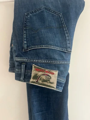 Blå jacob&cohen jeans - Säljer ett par blå jeans från jacob&cohen med klassisk femficksdesign och en unik patch med broderad logga på bakfickan. Jeansen har raka ben och är gjorda i slitstarkt denimmaterial. Perfekt för dig som gillar streetwear och detaljer.