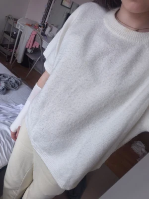 Vit stickad t-shirt med kort ärm - Säljer en enkel och stilren vit stickad t-shirt med korta ärmar och rund hals. Tröjan har en avslappnad passform och ribbade detaljer vid hals, ärmslut och nederkant. 💗