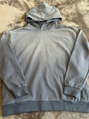 Acne Studios Hoodie Dust Blue - En stilren blå hoodie med huva och ribbade muddar vid ärmslut och nederkant. Hoodien har tryck på baksidan eller logga och har en avslappnad passform. Perfekt för dig som gillar en clean och enkel look. Materialet känns mjukt och bekvämt.
