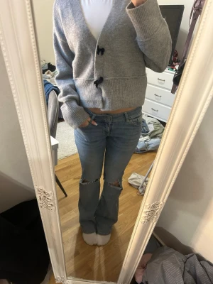 Ljusblå slitna bootcut jeans - Säljer ett par ljusblå bootcut jeans med slitningar och hål vid knäna. 