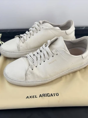 Vita sneakers från Axel Arigato - Snygga vita sneakers från Axel Arigato i stilren design med diskret logga på sidan och hälen. Skorna är i skinn och har klassisk snörning. Perfekta för dig som gillar minimalistisk och clean stil.