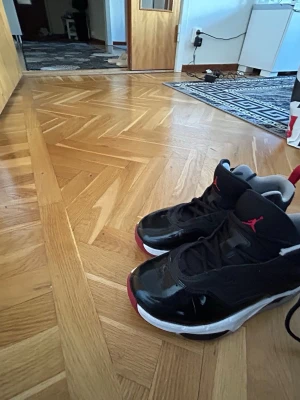 Svarta Air Jordan 11 Retro sneakers - Säljer ett par svarta Air Jordan 11 Retro sneakers med röda och vita detaljer. Skorna har en blank finish på tåpartiet, klassisk Jumpman-logga på plösen och sidorna samt vit sula. Perfekta för dig som gillar streetwear och ikoniska modeller.