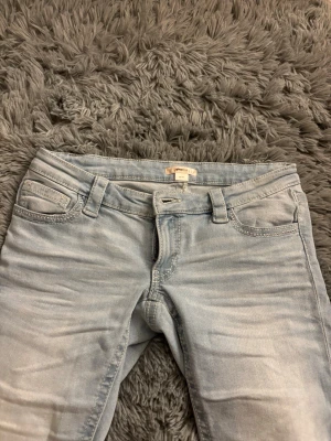 Ljusblå  jeans från Gina 14+ - Säljer ett par ljusblå skinny jeans från ginatricot med klassisk femficksdesign och snygga detaljer på bakfickorna. Jeansen har bälteshällor och är tillverkade i stretchigt denim för en bekväm passform. Aldrig använda helt nya endast testade