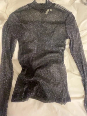 Glittrig svart topp - Säljer en svart glittrig fest tröja från Nelly , mycket bra skick, glittret ser ni bättre på sista bilden❣️