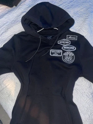 Svart hoodie från Mercier - Svart hoodie från Mercier med flera snygga patches. Storlek S men passar även M