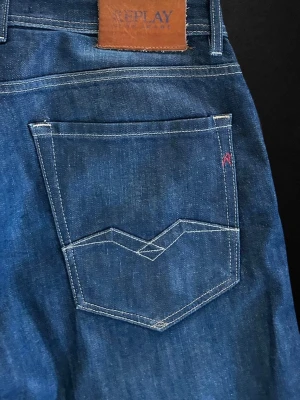 Replay jeans - Snygga mörkblå jeans från Replay med klassisk femficksdesign och coola kontrastsömmar på bakfickan. Jeansen har rak passform och är tillverkade i slitstark denim. Perfekta för en avslappnad och trendig look.