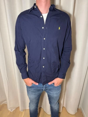 Marinblå Ralph Lauren skjorta  - Hej! Nu säljer vi denna Ralph Lauren skjortan i storlek M för endast 349kr men nypris ligger på 1449kr. Mycket bra skick och kan postas samma dag. // studio II Resell 