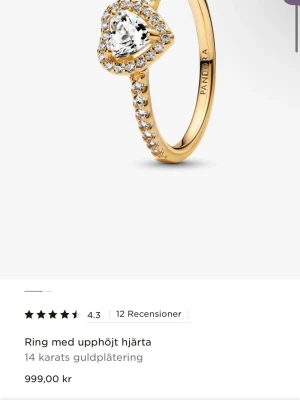 Pandora ring med hjärtformad sten - Superfin ring från Pandora i 14 karats guldplätering med en upphöjd hjärtformad klar sten i mitten och små gnistrande stenar runt om hela ringen. Perfekt för dig som gillar eleganta och romantiska smycken. 
