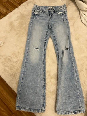Ljusblå bootcut jeans från Gina Tricot - Snygga ljusblå bootcut jeans från Gina Tricot med slitningar på båda benen och klassisk femficksdesign.