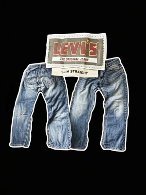 Vintage Levi’s Slim Straight Jeans  - Ett par klassiska blå Levi's jeans i modellen Slim Straight, men sitter mer som Straight/Relaxed med storlek W34 L32 men sitter som W32 L32. Jeansen har en riktigt snygg tvätt, och helt utan defekter. Tillverkade i bomull med fem fickor och gylf med knapp. Perfekta för en avslappnad och trendig look. Hör av dig vid minsta fundering⭐️Kan gå ner i pris vid snabb affär🤝Mått: Midja: 42cm | Innerbenslängd: 74cm | Benöppning: 21cm. 