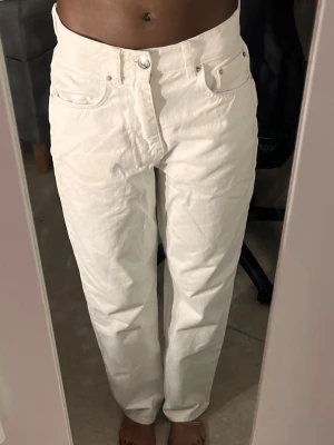 Vita raka jeans som är midwaist - Säljer ett par vita jeans med rak passform som är midwaist. Jeansen har klassiska fem fickor och bälteshällor. Perfekta för en clean och fräsch look. Materialet är denim och bekvämt. Jeansen är från Gina tricot och är knappast använda.