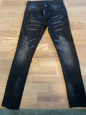 Svarta slim fit jeans med slitningar - Snygga svarta slim fit jeans med slitningar och färgstänk på framsidan. Jeansen har fem fickor, knappgylf och en tvättad look som ger en cool streetkänsla. Perfekta för dig som gillar en trendig och avslappnad stil. De passar perfekt för dig som är runt 170-175. PRISET ÄR EJ HUGGET I STEN, KOM MED PRISFÖRSLAG SÅ KAN VI TA DET DÄRIFRÅN!!