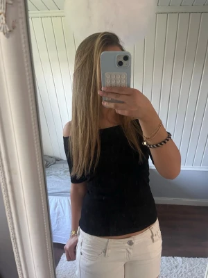 Svart offshoulder topp - Snygg svart offshoulder topp med tight passform. Perfekt att styla med jeans eller kjol för en trendig look. Toppens enkla design gör den lätt att matcha och den sitter skönt mot kroppen.