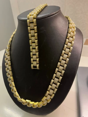 Guldhalsband med gnistrande stenar - Stilrent halsband i guldton med rektangulära länkar täckta av små gnistrande stenar. Kedjan har en chunky design som ger ett lyxigt intryck och passar perfekt för dig som gillar att sticka ut. Materialet är metall med glittrande dekorationer.