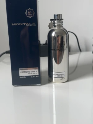 Montale Chocolate Greedy  - Montale Chocolate Greedy Eau de Parfum i en cool, spegelblank silverfärgad metallflaska. Doften är känd för sina söta chockadtoner. Kommer i en stilren mörkblå kartong med tydlig logga och etikett. 90/100