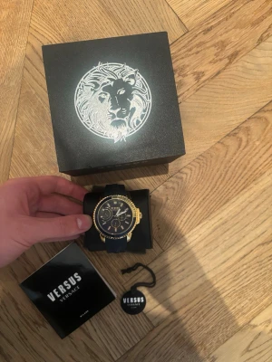 Äkta Versace klocka (nyservad) nypris: 3 137kr - Nyservad på klockmaster för 350kr. Nypris ligger på 3 137kr (se bild). All original tillbehör medföljder, dvs originallåda, orginal certifierings tagg, liten original broschyr. Stilren klocka från Versus Versace med blått armband och urtavla, samt detaljer i guld. Klockan har flera små urtavlor och tydliga indexmarkeringar. Snygg design med lyxig känsla, levereras i originalask.
