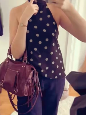 Svart prickig halterneck topp - Säljer en svart halterneck topp med mint prickar. Toppen är ärmlös och har öppen rygg med knyt i nacken. Perfekt för dig som gillar en cool och trendig look. Materialet känns lätt och luftigt, perfekt för varma dagar.