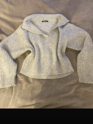 Ljusgrå stickad tröja Gina Tricot - Mysig ljusgrå stickad tröja från Gina Tricot med krage och v-ringning. Tröjan har breda ärmar och är ribbstickad i ett mjukt material, perfekt för lager på lager. Enkel och stilren design som passar till det mesta.