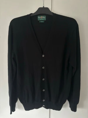 Alan Paine kofta L - Svart snygg helt ny Alan Paine kofta i merinoull och storlek L säljes. Grym passform. Utmärkt skick då den är i absolut nyskick och tveka inte vid minsta fråga eller fundering!