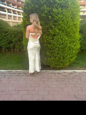 Ljusgrön långklänning med öppen rygg (limited edition nakd) - Säljer en elegant ljusgrön långklänning med subtilt blommigt mönster. Klänningen har öppen rygg, tunna axelband och en mjuk, glansig finish som påminner om satin. Perfekt för sommarens alla tillfällen!