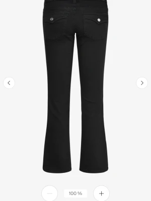 Svarta bootcut jeans med fickdetaljer - Snygga svarta bootcut jeans med klassiska fem fickor och silverfärgade knappar. Jeansen har utsvängda ben och markerade bakfickor med lock och knapp. Perfekta för en trendig och avslappnad stil.