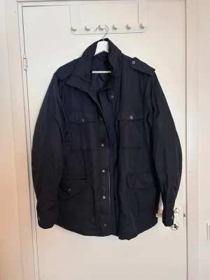 Svart parkajacka Tiger of Sweden - Snygg marinblå parkajacka från Tiger of Sweden med flera fickor och hög krage. storlek 50 (herr). Köpt för några år sedan, tror ej den säljs längre då jag inte hittar någonstans