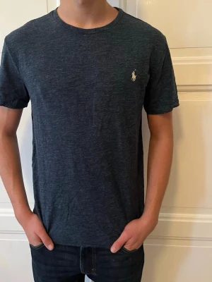 Mörkblå t-shirt från Polo Ralph Lauren - Snygg mörkblå t-shirt från Polo Ralph Lauren med klassisk passform och ikoniska loggan broderad på bröstet. Tillverkad i mjuk bomull och har rund halsringning samt korta ärmar. Perfekt till jeans eller shorts.