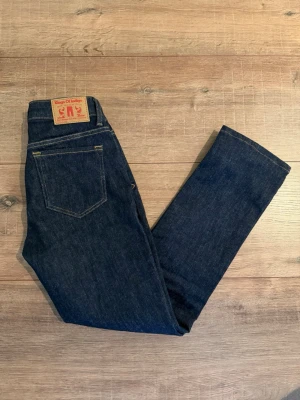 Mörkblå jeans från Kings of Indigo 25:28 - Säljer ett par mörkblå jeans från Kings of Indigo med klassisk femficksmodell och raka ben. Jeansen har snygga kontrastsömmar och är tillverkade i slitstarkt denimtyg. Perfekta för dig som gillar tidlös och clean stil. Upplagda 3 / 5 cm så det är som en 28 längd. 