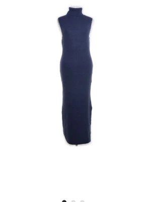 Marinblå stickad långklänning - Säljer en marinblå stickad långklänning med polokrage och ärmlös design. Klänningen har en figurnära passform och är perfekt för dig som gillar en stilren och enkel look. Materialet är mjukt och stretchigt för extra komfort.