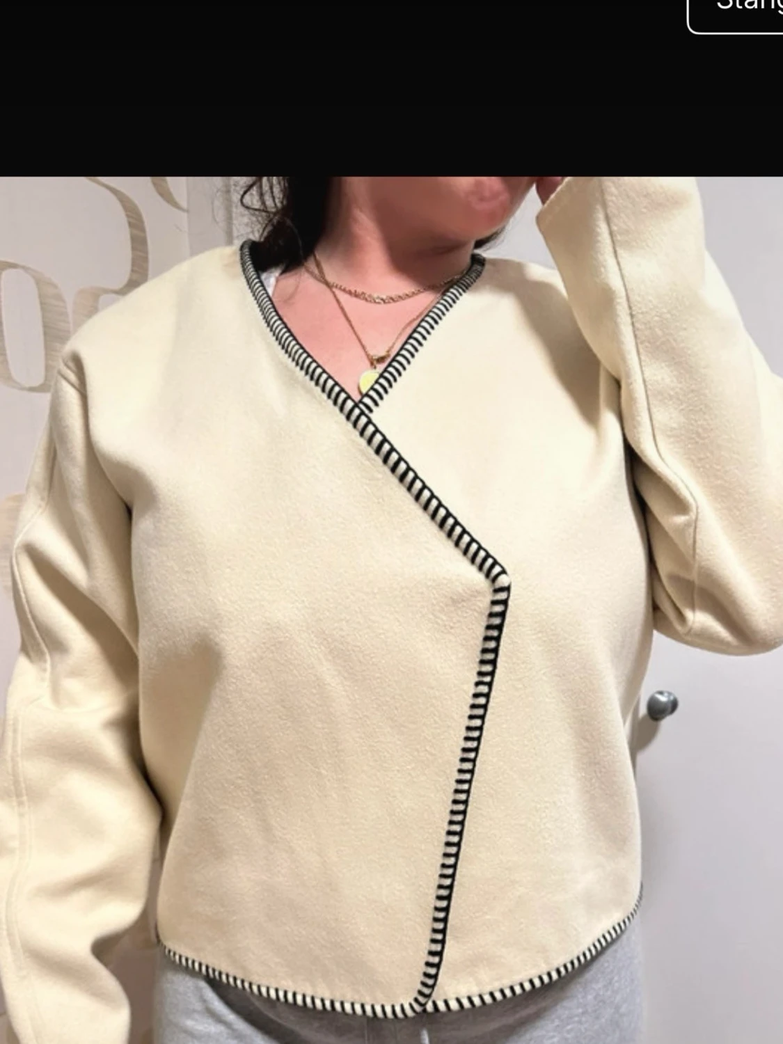 Beige omlottkofta med svarta detaljer