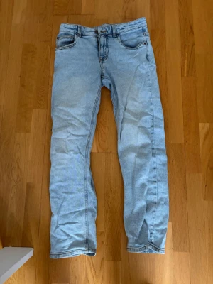 Ljusblåa jeans - Säljer ett par ljusblå jeans med klassisk femficksdesign och raka ben. Jeansen har normal midja och är tillverkade i ett mjukt denimtyg. Perfekta för en avslappnad och trendig look. Tveka inte på att höra av dig vid funderingar!