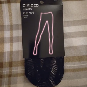 HELT NYA OANVÄNDA Svarta nätstrumpbyxor / strumpbyxor / tights från Divided. XS/S - HELT NYA OANVÄNDA svarta nätstrumpbyxor från Divided, H&M, i storlek XS/S. Tightsen har ett snyggt mönster som ger en edgy vibe och passar perfekt till kjol eller shorts. Materialet är mjukt och stretchigt polyester och elastan för skön passform. Felfria.