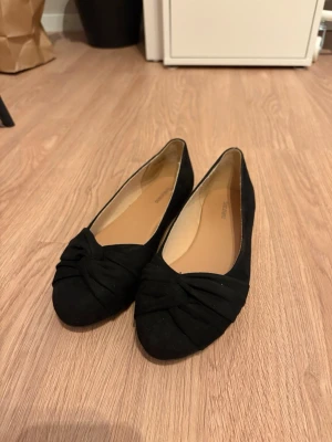 Svarta ballerinaskor från Graceland - Snygga svarta ballerinaskor från Graceland med twistad detalj framtill. Skorna har rundad tå och är gjorda i ett mjukt tygmaterial med beige innersula. Perfekta för dig som vill ha en stilren och enkel look. Finns även på Vinted 