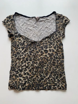 Leopardmönstrad v-ringad topp - Kortärmad topp med leopardmönster och djup v-ringning. Tunn och mjuk känsla, perfekt för dig som vill sticka ut. Toppen har en figurnära passform och är lätt att matcha med både jeans och kjol.