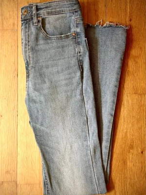 Flared jeans with slit - Jeans från Stradivarius. Högmidjade jeans med fem fickor och hällor för bälte. Modellen har utsvängda ben med fransiga detaljer och en slits på insidan av bensluten. Gylf med dragkedja och knapp i metall framtill. Innerbenslängd: 77 cm.