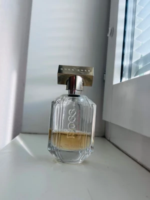 Hugo Boss The Scent Eau de Parfum - Elegant parfym från Hugo Boss i en genomskinlig, multifacetterad glasflaska med silverfärgat lock. Doften är varm och sensuell, perfekt för dig som vill ha en lyxig och modern signaturdoft.
