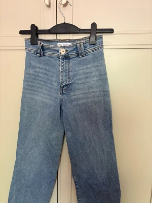 Ljusblå raka jeans från Zara - Ljusblå jeans från Zara i rak modell med klassisk femficksdesign och bälteshällor. Jeansen har en snygg tvättad look och stängs med knapp och dragkedja. Perfekta för en avslappnad stil.