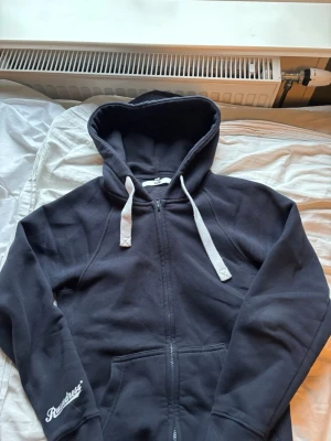 Marinblå Zip-Hoodie från Russemerch! - Mysig marinblå hoodie från Russemerch i storlek XS. Hoodien har dragkedja framtill, stora fickor och vit dragsko i huvan. Mjuk insida och logga på ärmen. Perfekt för chill dagar eller när du vill ha en enkel och clean look. Nypris 750kr, mitt pris 500kr.