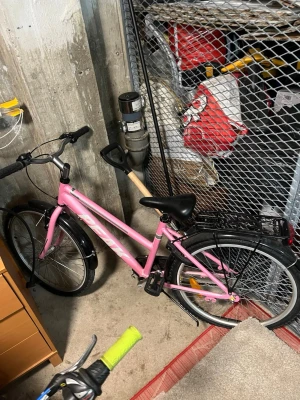 Rosa cykel med pakethållare - Säljer en rosa cykel med svart sadel, svarta handtag och pakethållare bak. Cykeln har klassisk ram, reflexer och stänkskärmar. Perfekt för dig som vill ha en snygg och praktisk cykel till vardags. Pedaler och handtag i plast, ram i metall.