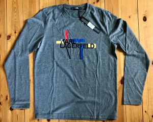 Grå långärmad t-shirt/kofta Karl Lagerfeld - Snygg grå långärmad t-shirt/kofta från Karl Lagerfeld med färgglatt tryck i rött, blått, gult och svart framtill. Tillverkad i mjuk bomull och har en klassisk rund hals. Perfekt för dig som vill ha en stilren men ändå unik look.