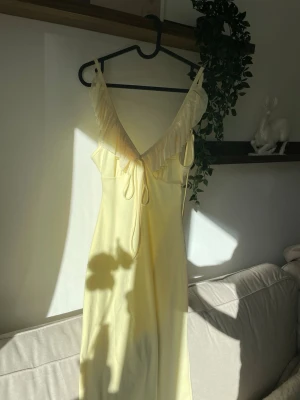 Gul lång klänning från SHEIN - Gul klänning med öppen rygg och volanger ovanför brösten. Perfekt klänning inför sommaren. Den går hela vägen ner på mig som är 163 cm lång, mycket bra passform.