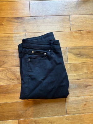 Svarta slim fit jeans från Jack & Jones - Snygga svarta slim fit jeans från Jack & Jones med klassisk femficksdesign och metallnitar. Jeansen har en smal passform och är tillverkade i ett stretchigt bomullsmaterial för extra komfort. Perfekta för en stilren och modern look. Storlek 30/30 bara använda fåtals gånger!