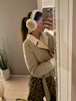 Beige mocka jacka - Snygg beige jacka i mocka i vit fuskpäls. Jackan har en rak passform och bälte i midjan för extra stil. Storlek 34 och sparsamt använd. 