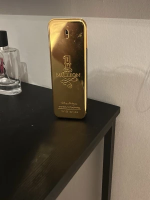 Paco Rabanne 1 Million EdT 100ml - Säljer en ikonisk parfym från Paco Rabanne, 1 Million EdT 100ml. Flaskan har en unik guldfärgad design som liknar en guldtacka och är tillverkad i metall och plast. Doften är maskulin och lyxig, perfekt för dig som vill sticka ut. Ingen parfym i den