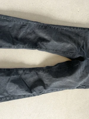 Svarta bootcut jeans med fickor - Snygga svarta bootcut jeans med klassiska bakfickor och normal midja. Jeansen har en lätt tvättad look och är tillverkade i ett mjukt denimtyg som ger en avslappnad känsla. Perfekta för dig som gillar en retroinspirerad stil.